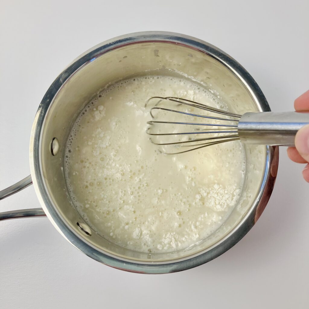 Whisking flour and water in a small saucepan.