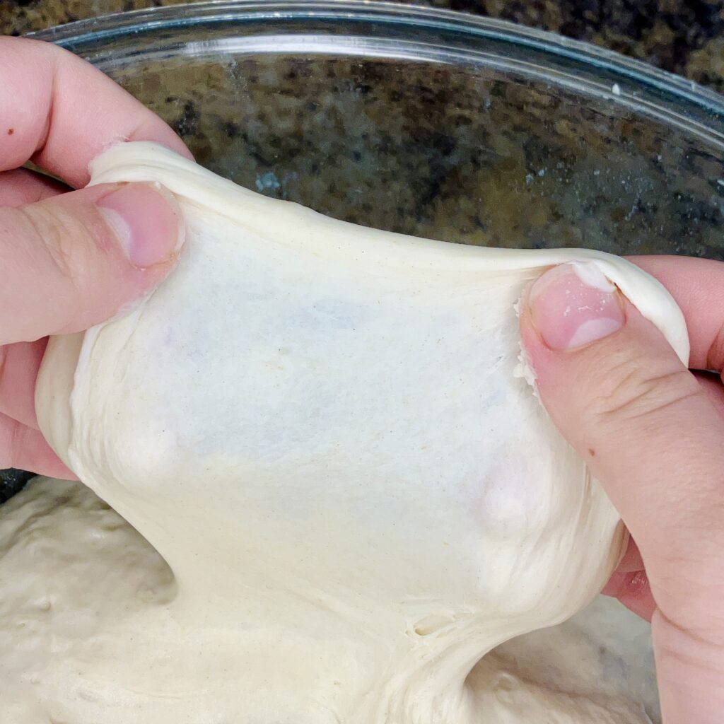 Dough being stretched to show a strong windowpane